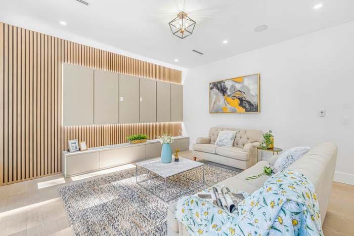 Modern living room featuring wood slat wall paneling, beige sofas, and a marble coffee table.